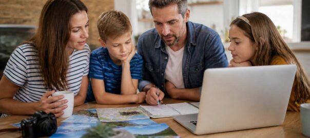 Gezin dat vakantieopties vergelijkt aan tafel met laptop en notitieboek