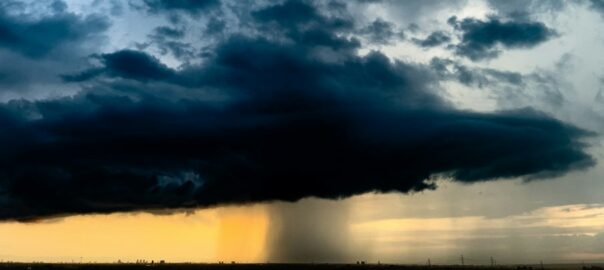 A very large cloud in the sky over a field